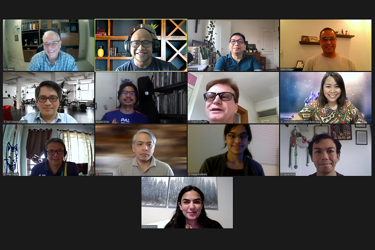 A video-call grid of 13 smiling participants on camera from their homes and offices during an online class