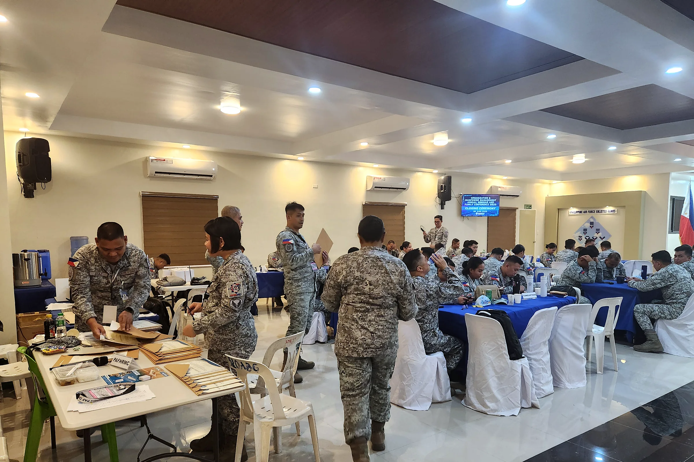 Philippine Air Force personnel in camouflage uniforms gathered around a table with workshop materials in a function room